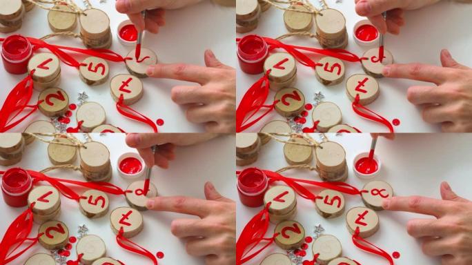 画，为圣诞节和新年的孩子们制作一个降临日历。女人的手拿着毛笔，写一个数字。日历日。装饰用木制坯料。侧