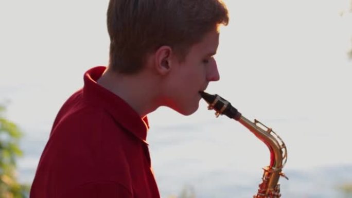 日落时，一个年轻人在河岸附近演奏萨克斯管。