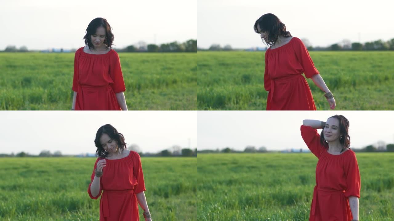 日落或黎明时，穿着红色连衣裙的美丽年轻女子走在绿色的麦田里