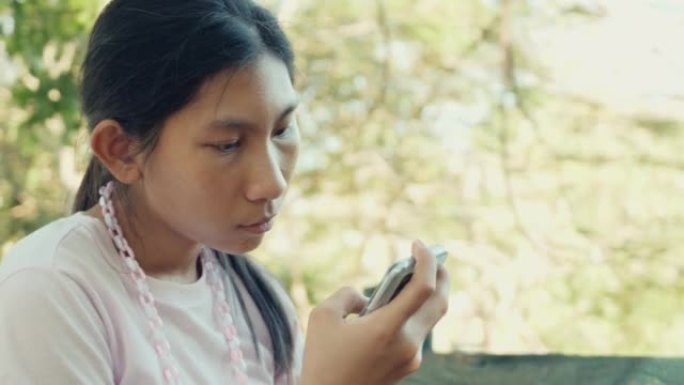 亚洲女孩在公园户外通过智能手机观看病毒视频或电影，生活方式概念。