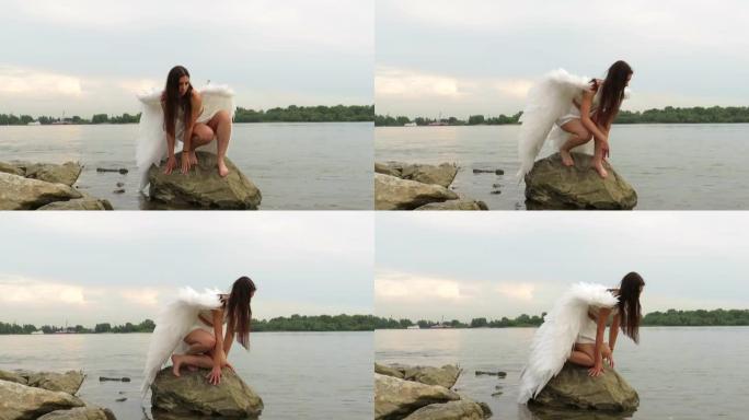 一个年轻的美丽的女人，在河上的一块巨石上有一个白色的翅膀的天使的形象