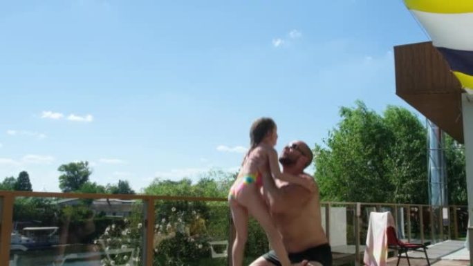 一个坚强的父亲把他的女儿高高抛向空中，在夏天捕捉大自然。