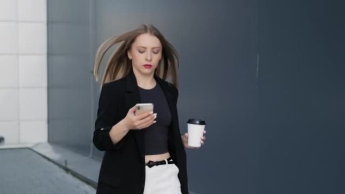 女商人用手机打字短信拿着一杯咖啡