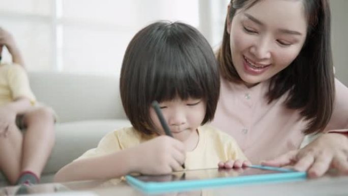 父亲母亲照顾，教导和帮助儿子在平板电脑和笔记本电脑上使用想象力并学习社交媒体知识，在家里的客厅享受假