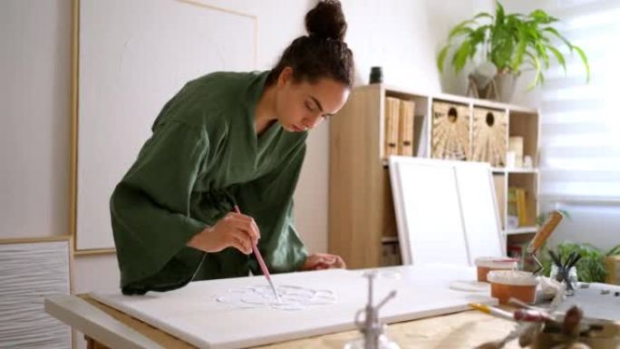 高加索女艺术家用尖锐的腻子和画笔在画布上创作艺术
