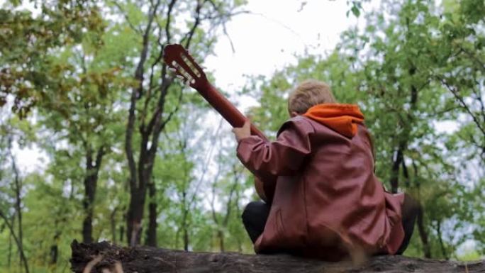 树林里手里拿着吉他的男孩