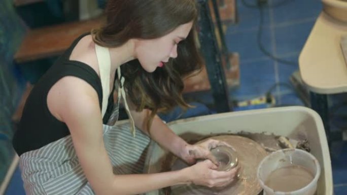 女工匠在纺纱机上用瓷土制作花瓶。