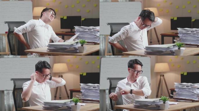 亚洲男子在办公室努力处理文件时腰酸背痛