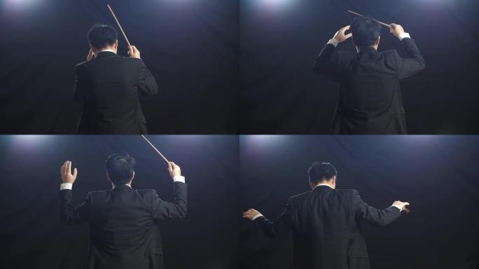亚洲指挥家男子手持指挥棒在黑色工作室展示手势的背影