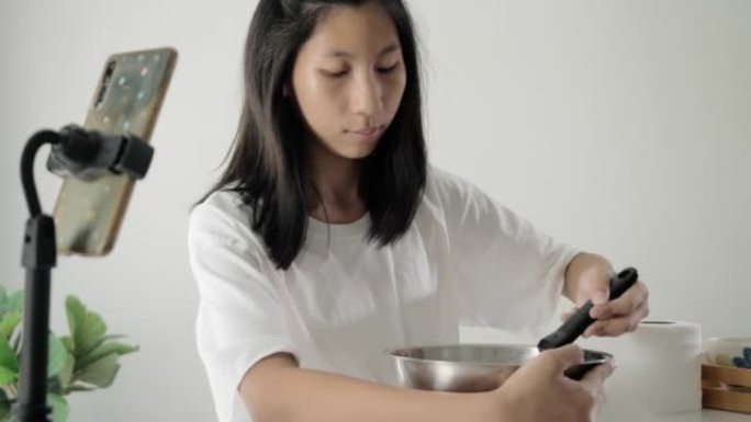 亚洲女孩在家智能手机制作视频处理自制冰淇淋，生活方式理念。