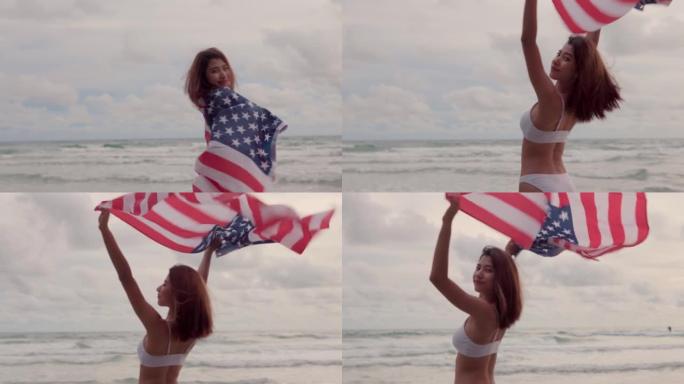 年轻的亚洲女性在海滩上享受时光，夏天在海滩上的日落天空上举着美国国旗，并在户外挥舞着美国国旗，独立纪