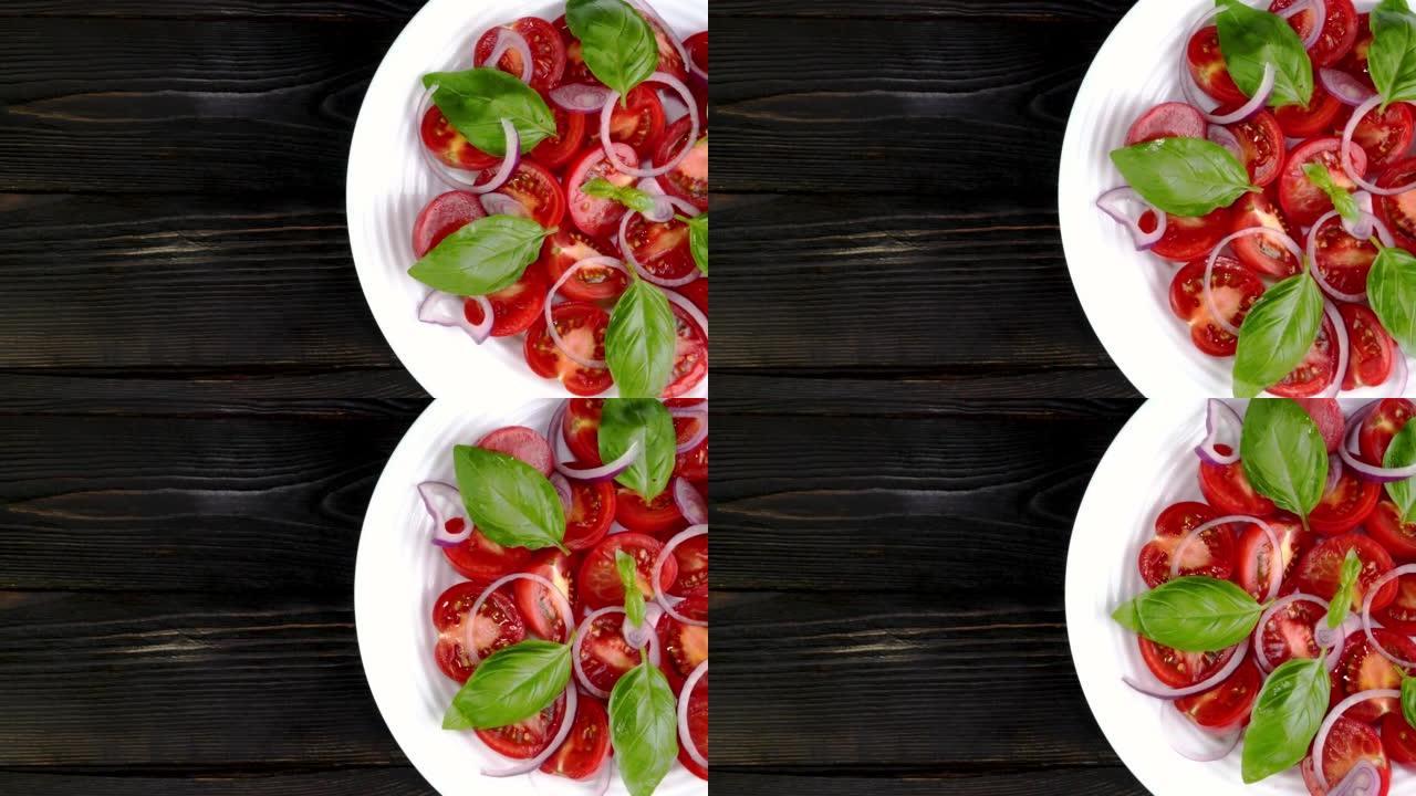 番茄沙拉配罗勒和切碎的洋葱在白色陶瓷盘中缓慢旋转。