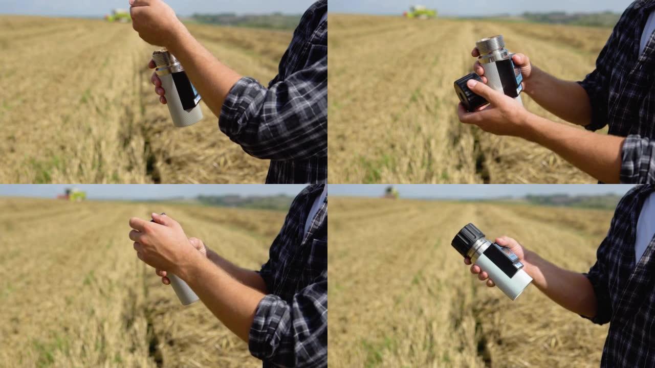 年轻的农民用特殊设备检查小麦的状况。联合收割机在后台工作
