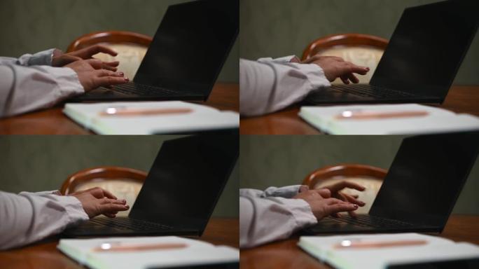 女商人的特写镜头，记者用手在笔记本电脑键盘上打字，写文本。桌子上有笔的笔记本