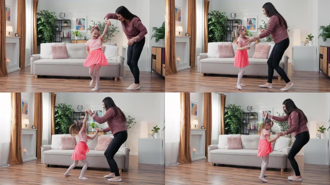 开朗的母亲小女儿站在家里的客厅里，一起跳舞着最喜欢的歌曲。孩子和姐姐保姆或爱心妈妈玩得开心积极休闲和