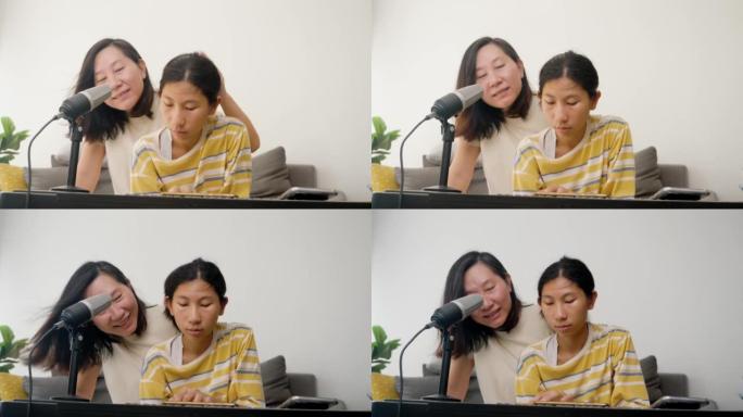 快乐的亚洲妈妈和正在玩电钢琴的女儿一起在沙发上唱歌，一起坐在家里的沙发上，生活理念。