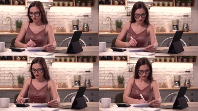 4k室内视频，年轻的欧洲女性坐在家里的桌子上用铅笔在纸上阅读数据，以便找出重要的东西并检查它，感到放