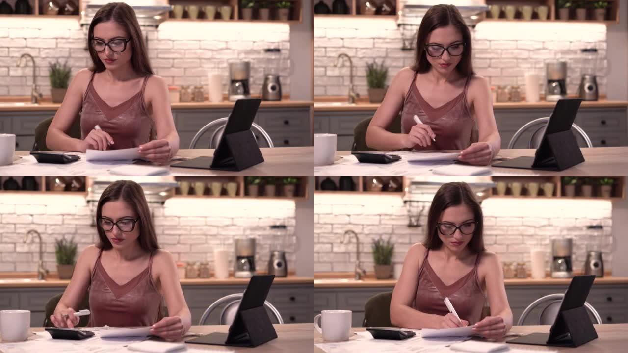 4k室内视频，年轻的欧洲女性坐在家里的桌子上用铅笔在纸上阅读数据，以便找出重要的东西并检查它，感到放