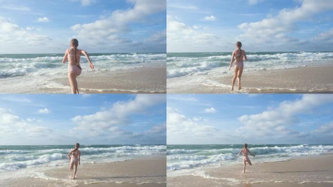 一个长发的少女沿着大西洋海岸奔跑，跳得很高。一个孩子在海滩上玩耍的全高清慢动作视频。