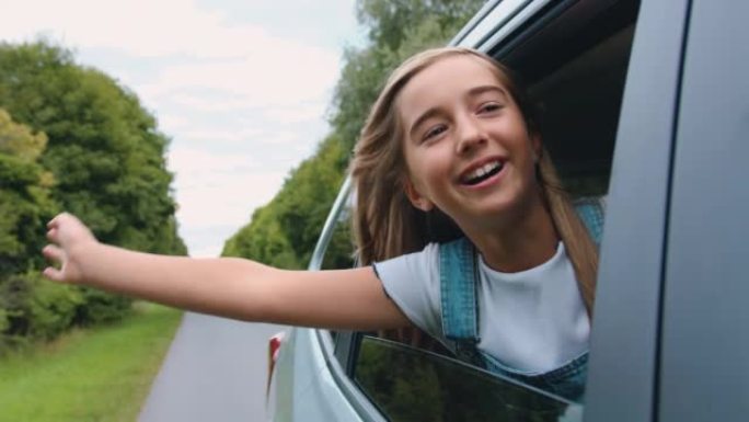 车窗里快乐的smoll女孩。微笑的孩子在一次家庭旅行中向外张望，挥舞着车窗的手