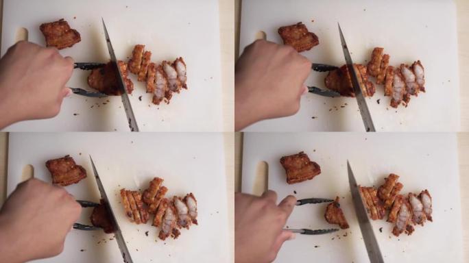 在家用厨房用菜刀在船上切或切炸猪肚肉。高胆固醇食物在高角度烹饪