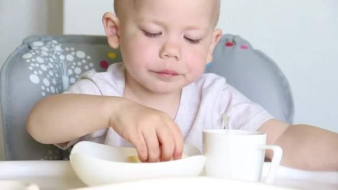 一个短发的小孩用玉米棒开胃地嘎吱嘎吱地喝，用吸管喝果汁。