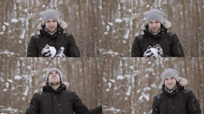 男人做雪球，扔它并拍手，男人对着镜头微笑。