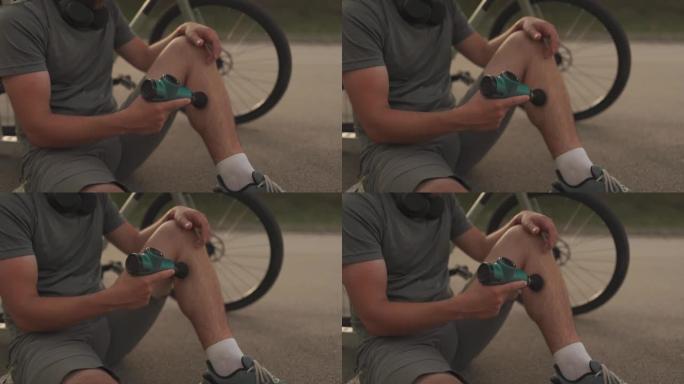 骑自行车的人在骑自行车锻炼后用按摩敲击器按摩肌肉和肌腱。运动员用手中的电动手枪按摩器按摩肌肉。运动恢