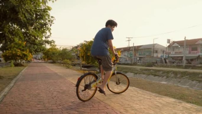 亚洲少年男孩骑自行车在户外的道路上，生活方式的概念。