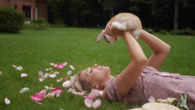 夏天，美丽的年轻女子躺在绿色的草地上，抱着一只复活节兔子