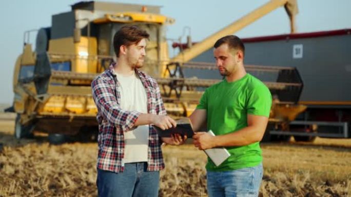农民，物流代理商签署粮食供应协议，在麦田握手。农学家讨论农业业务合同。牧场主，房东用握手谈判。收割机