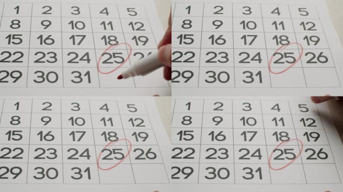 人的手用红笔在纸质日历上写下第25天。