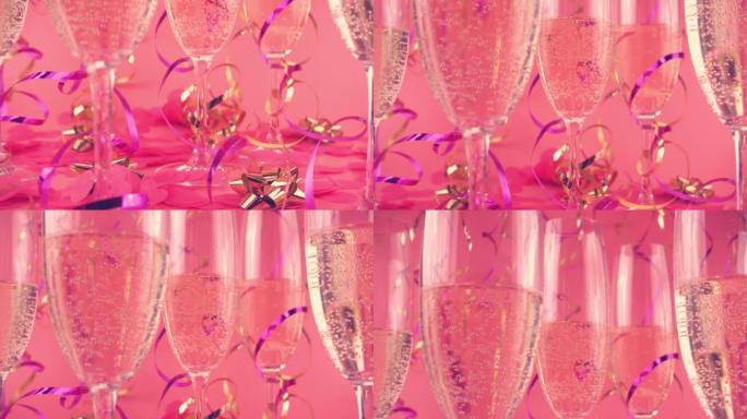 在粉红色背景的玻璃杯中起泡葡萄酒，带有五彩纸屑，呈心形和蛇形。