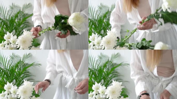 特写镜头，一个长发的花店女孩从美丽精致的白菊花茎上取下叶子，没有脸，只有手。