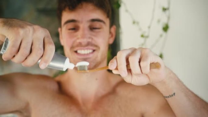 肌肉男在浴室把牙膏涂在牙刷上
