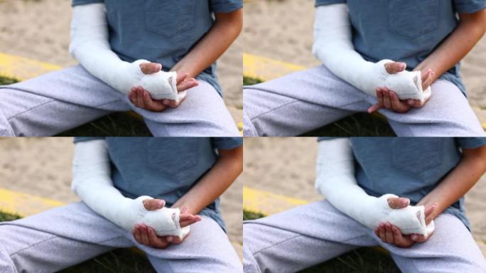 一个孩子的胳膊断了。在户外四肢骨折的小男孩。暑假骨折损伤。孩子正在用石膏在手臂上移动手指