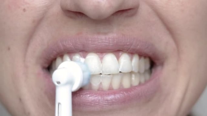 女人用电动牙刷清洁牙齿特写嘴