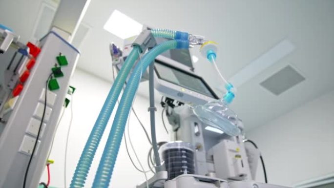 现代化的手术室，配备先进的设备。氧气面罩，蓝色管悬挂在肺通气设备附近。低角度视图。