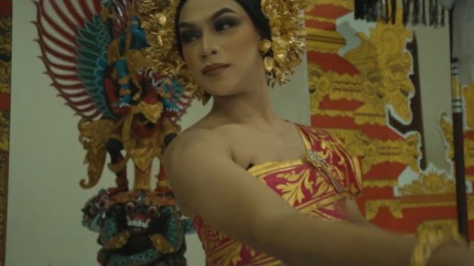 一位美丽的巴厘岛妇女在头上戴着金冠的装饰大门前跳舞