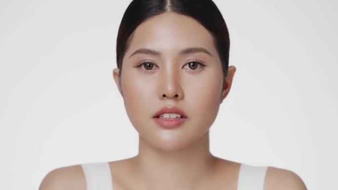 美丽的亚洲女性模特，完美清新干净的皮肤抬头看着相机，孤立在白色背景上。护肤治疗或化妆品广告概念。