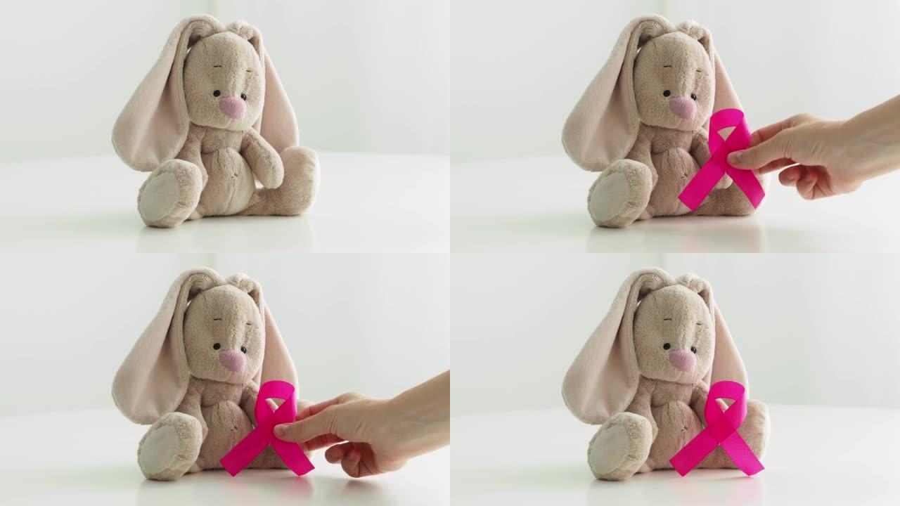 可爱的儿童玩具与粉红色的丝带-乳腺癌的象征。婴儿背景乳腺癌宣传月。儿童疾病。粉色蝴蝶结-希望和恢复的