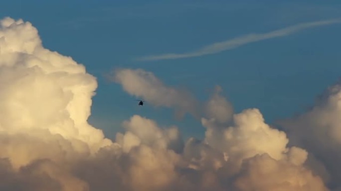 黑色小型直升机在美丽的日落积云和蓝天上空飞行