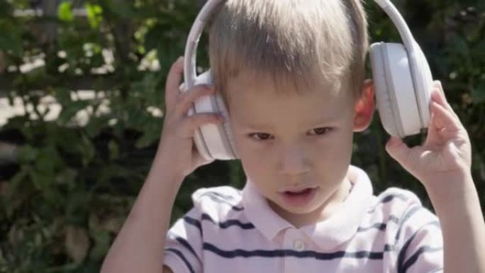 戴着耳机听音乐的可爱的小男孩的肖像。快乐无忧无虑的童年。学龄前女孩感到自由和时髦，良好的情感生活。孩