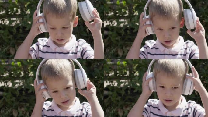 戴着耳机听音乐的可爱的小男孩的肖像。快乐无忧无虑的童年。学龄前女孩感到自由和时髦，良好的情感生活。孩