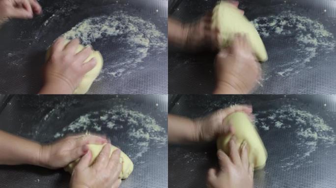 女性的手在金属表面上揉面团，制成低碳水化合物的酮百吉饼
