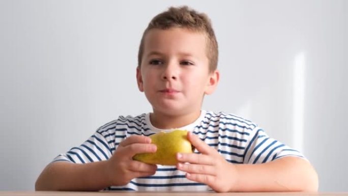 一个小男孩正在吃多汁的梨，看着相机。
