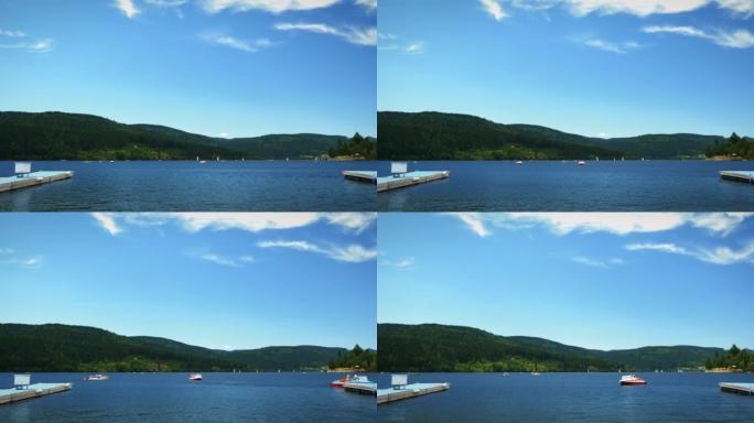 美丽的山湖，有浮动的电动船和船只，游客和人们在假日周末放松。碧水小湖，绿树群山环绕。自然景观