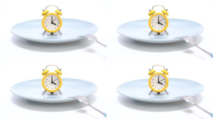白色背景的空盘子上有闹钟和叉子，间歇性禁食的概念。