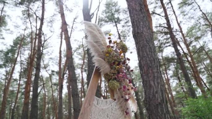 森林背景下带有鸵鸟羽毛和花朵的乡村婚礼拱门