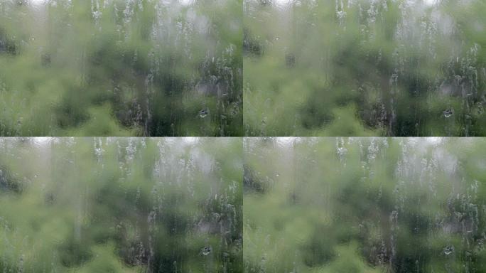 大雨。夏日的雨滴在窗户玻璃上。选择性聚焦，浅景深。水滴落在潮湿的窗户上。倾盆大雨时装满水滴的玻璃。全